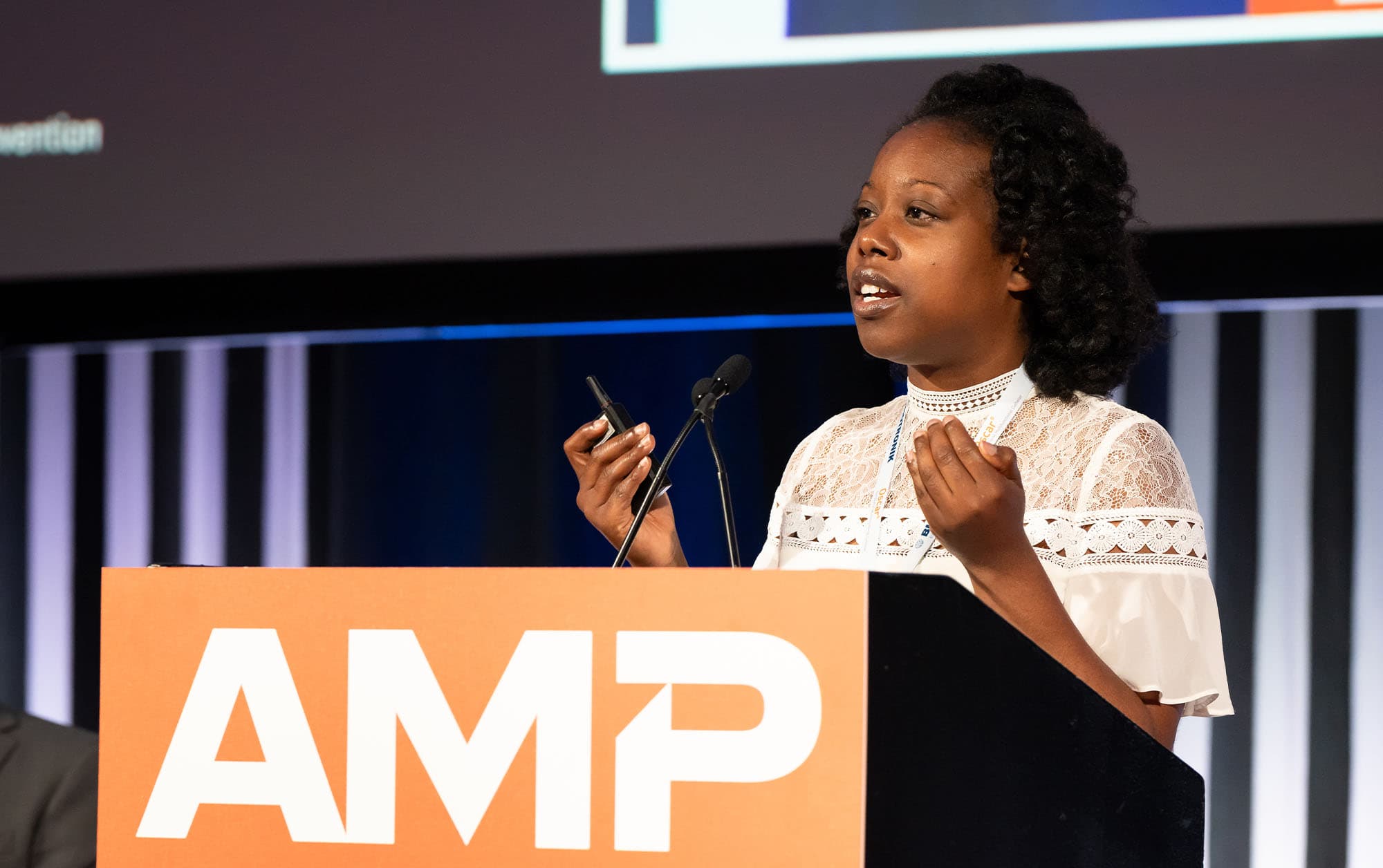 Woman standing in front of a lectern with the AMP logo on it