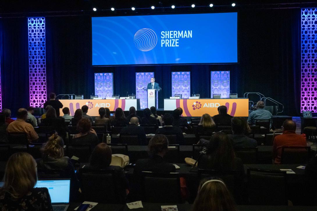 Crowd of people facing a stage with "Sherman Prize" on the screen